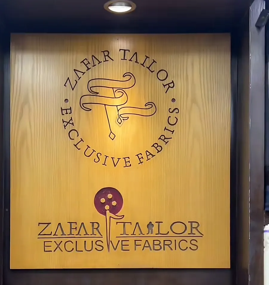 The gold Zafar Tailor Exclusive Fabrics board inside the shop