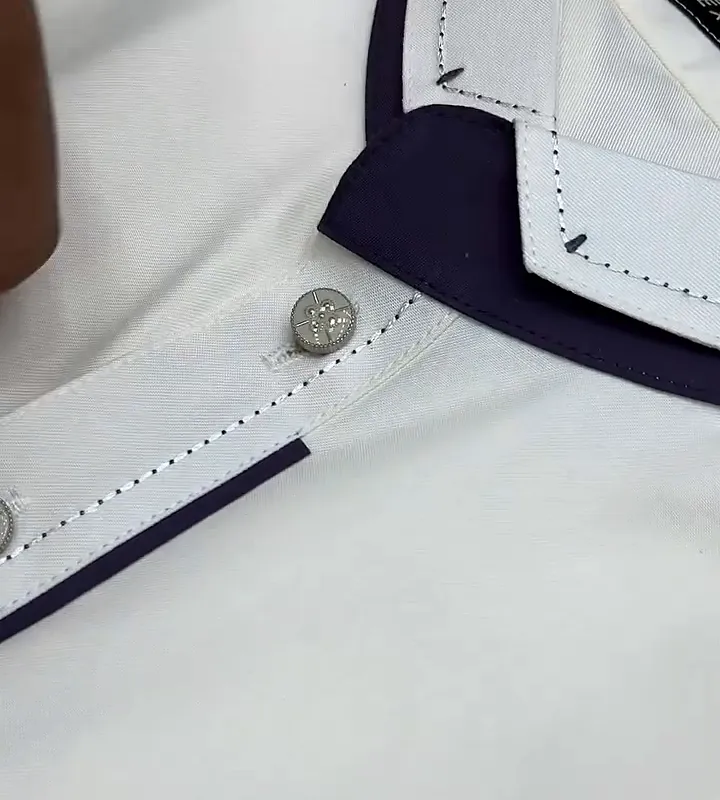 Close-up of a cream kameez: navy collar band, a stitch line along the placket and a metal button