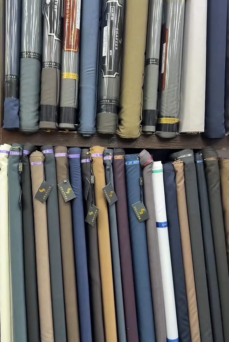 Shelves of suiting fabric in greys, blues, browns and creams at the shop